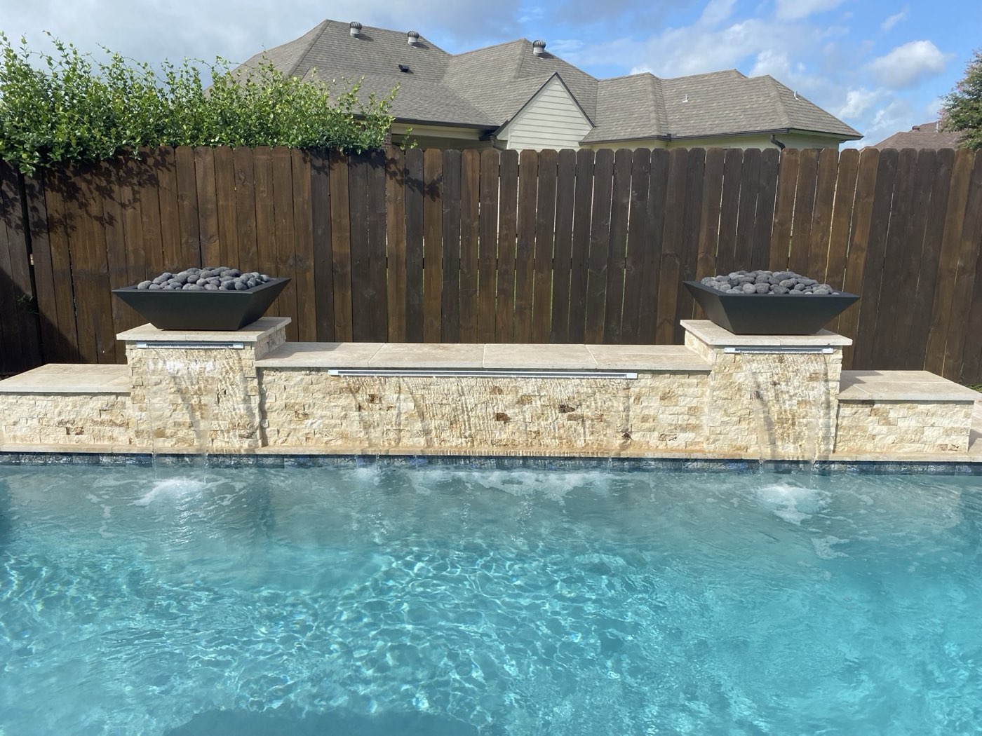 Stacked stone raised wall with sheer descent water features and fire bowls