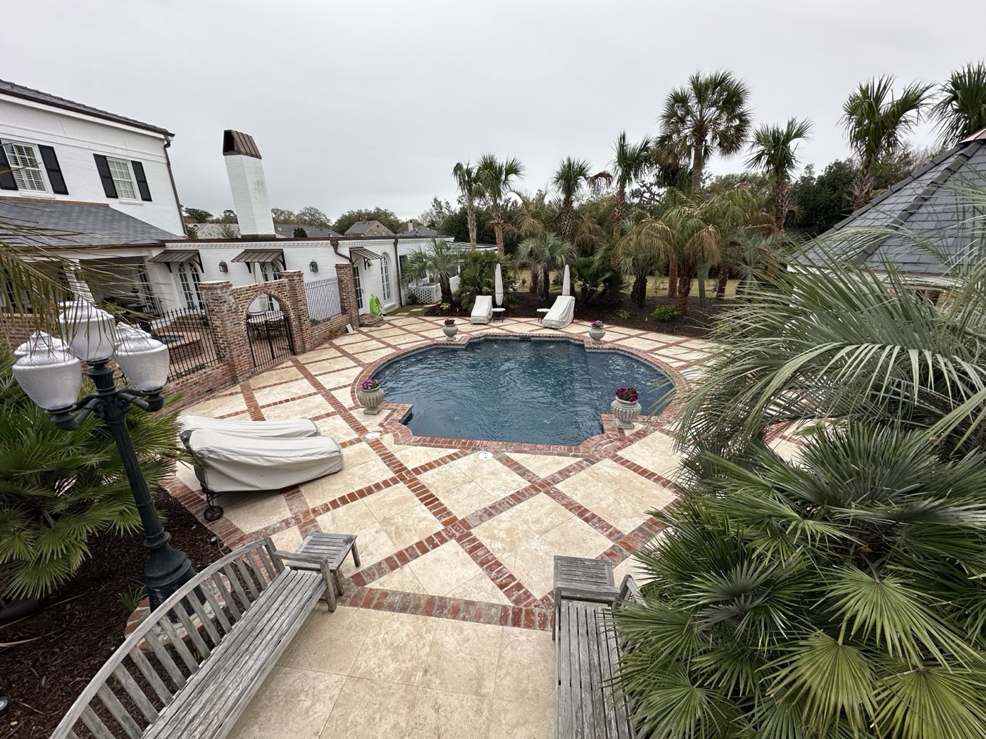 Elevated view of freeform pool with brick and travertine deck in estate setting