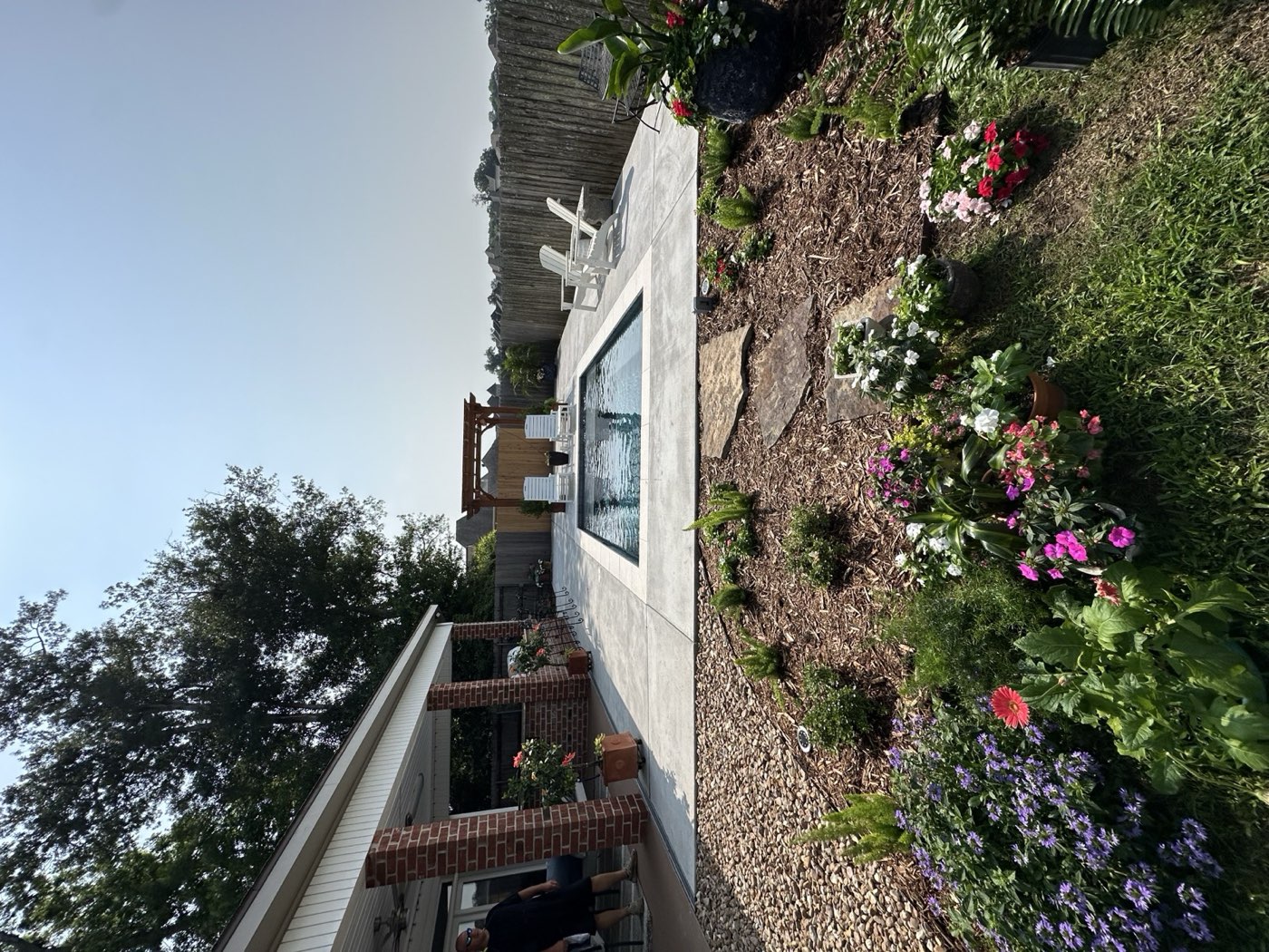 Rectangular pool with concrete deck, pergola, and flower garden
