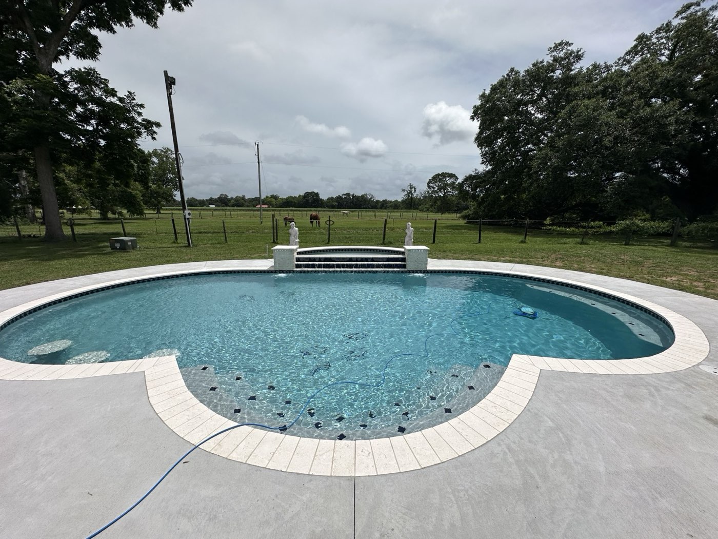 Freeform pool with raised wall water feature in rural setting