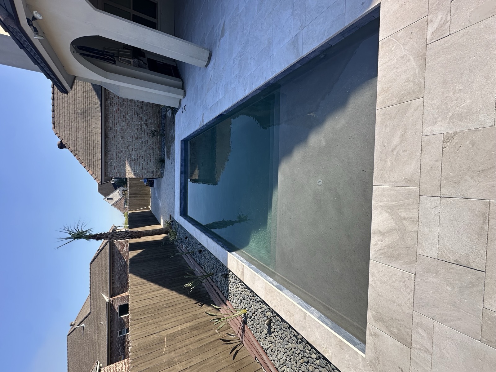 Sleek rectangular pool with travertine deck and river rock landscaping