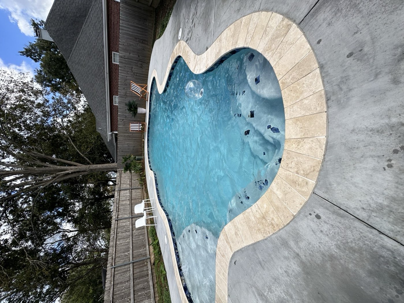 Freeform pool with travertine coping and concrete deck