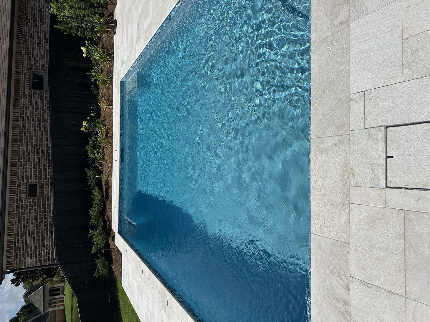 Rectangular pool with travertine coping and fresh landscaping
