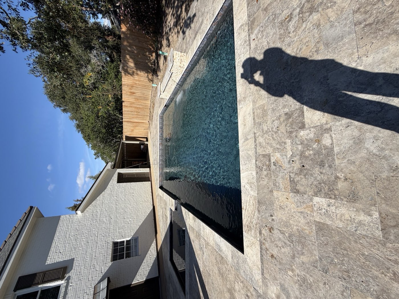 Rectangular pool with stone water feature and travertine deck