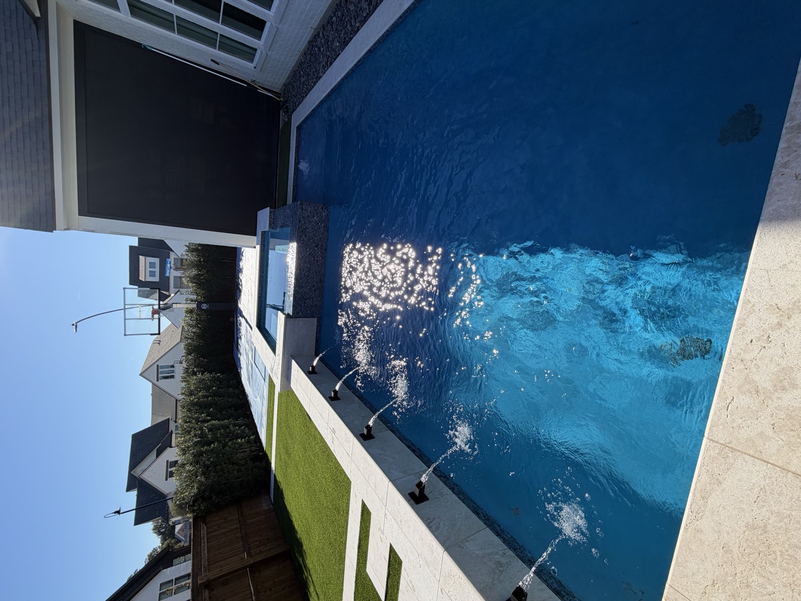 Pool with scuppers, spa, and turf with sun glare
