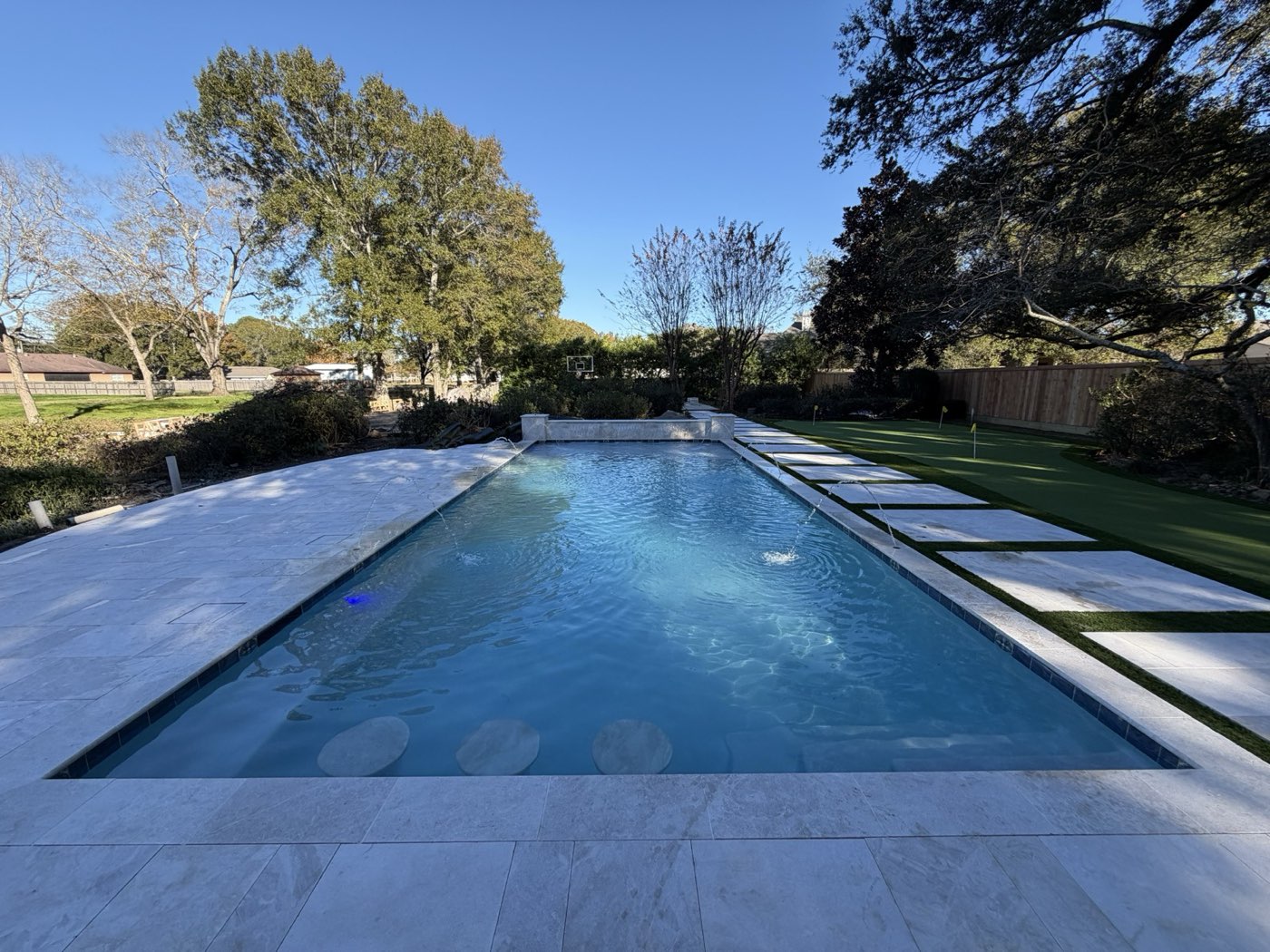 Long rectangular pool with stepping stones, turf, and putting green
