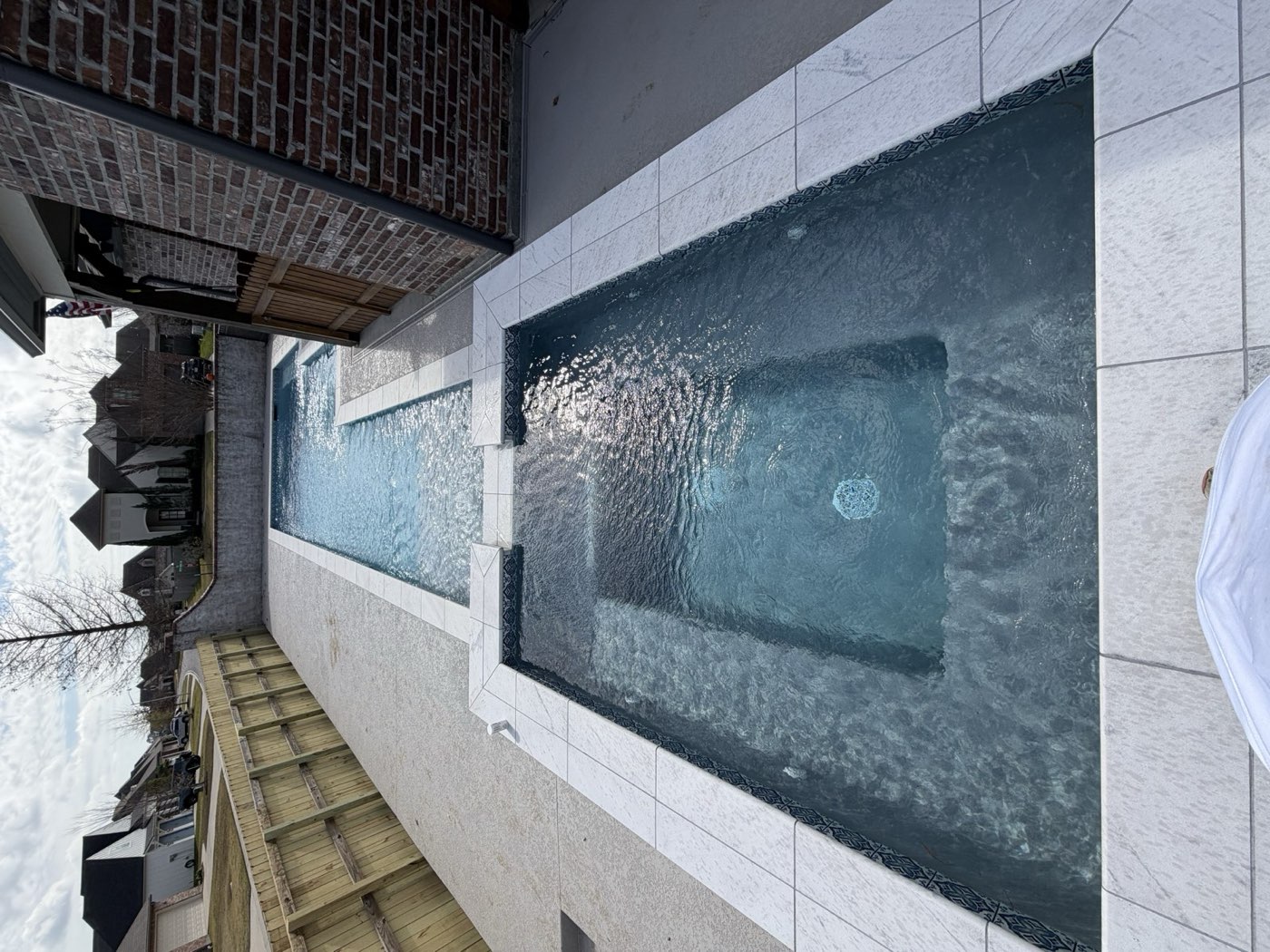 Narrow pool with spa and spillover in residential neighborhood
