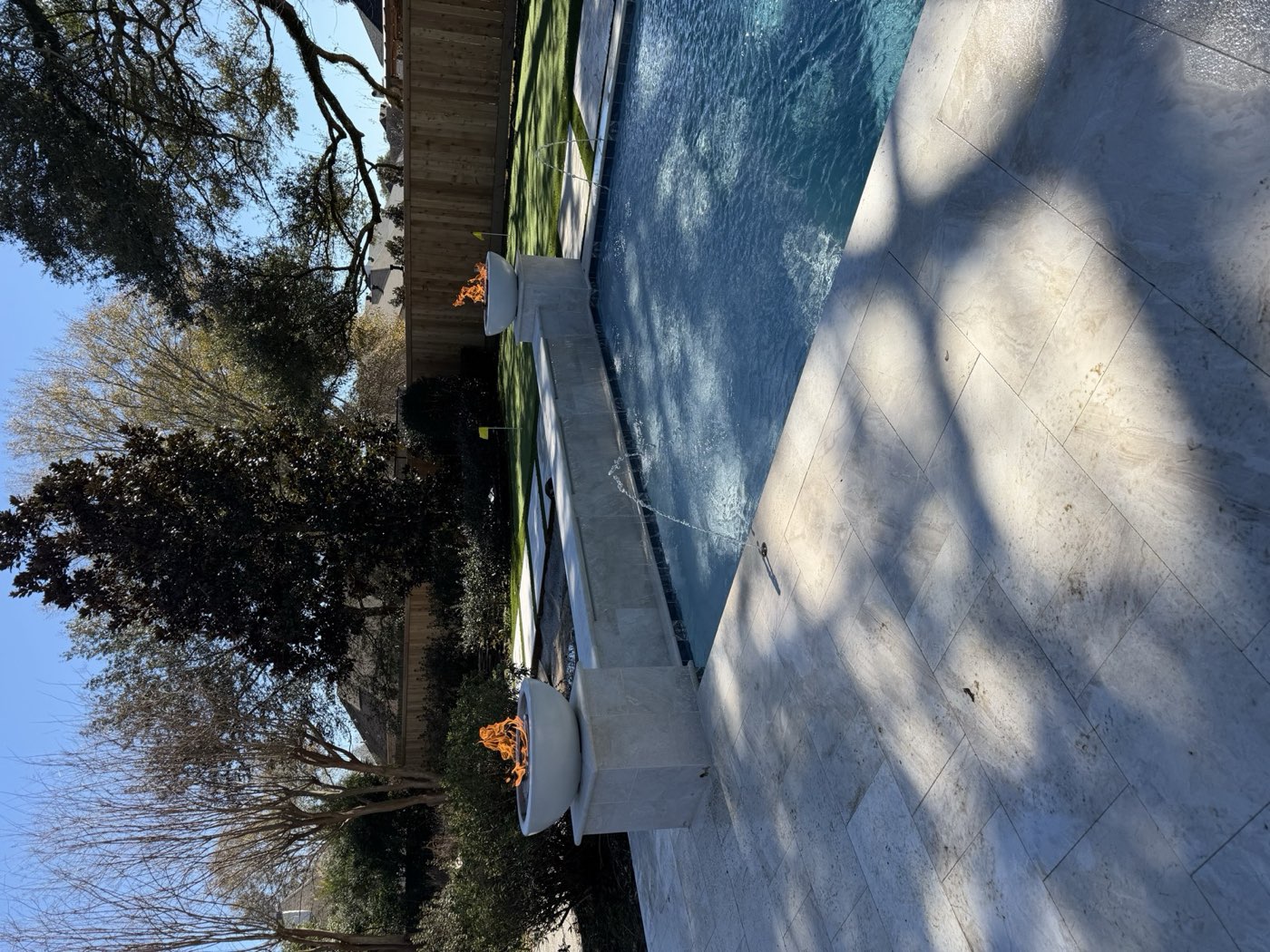 Rectangular pool with fire bowls, deck jets, and putting green